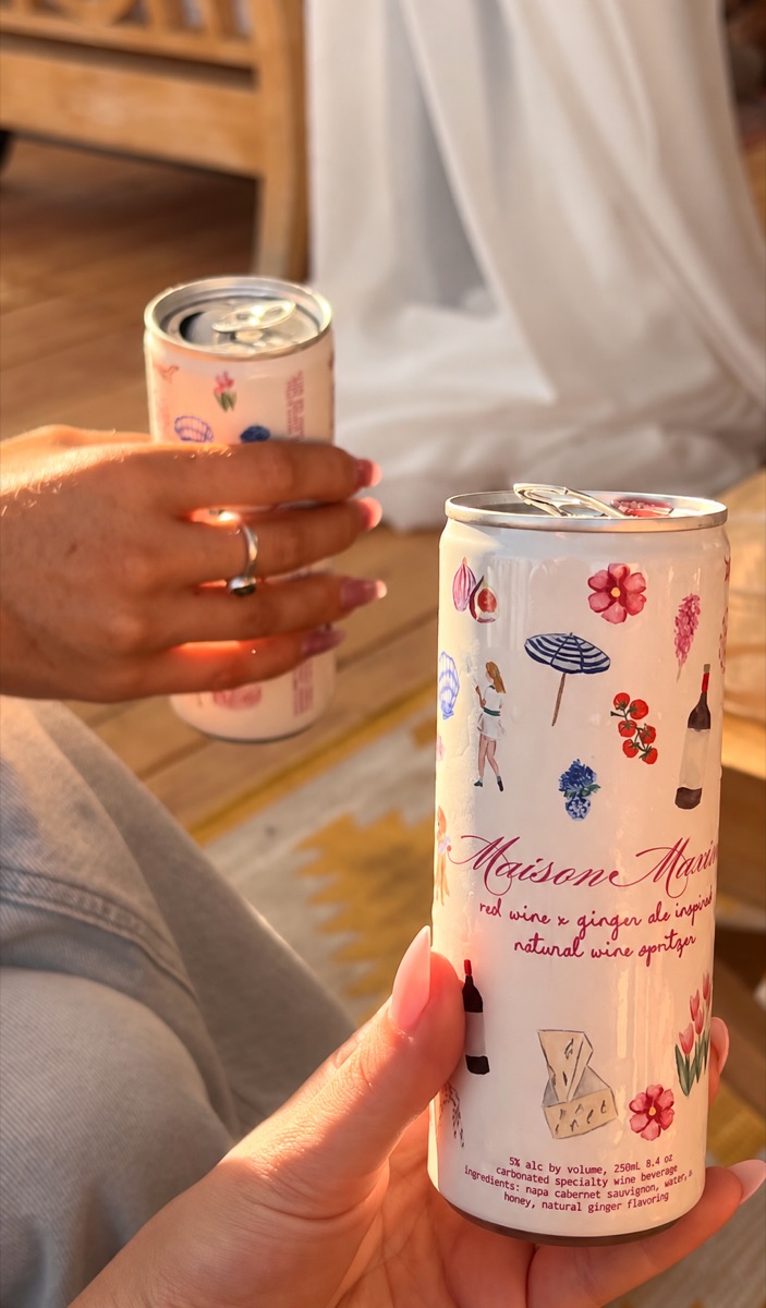 two maison maxine cans raised in a toast at golden hour