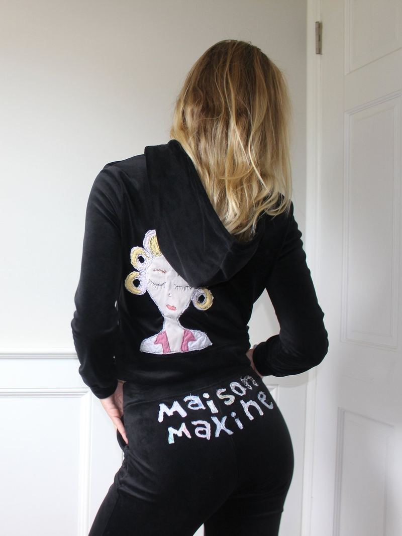 black velour maison maxine hoodie and matching velour flare leggings, with an appliqué girl in curlers on the back and maison maxine hand-lettered across the leggings