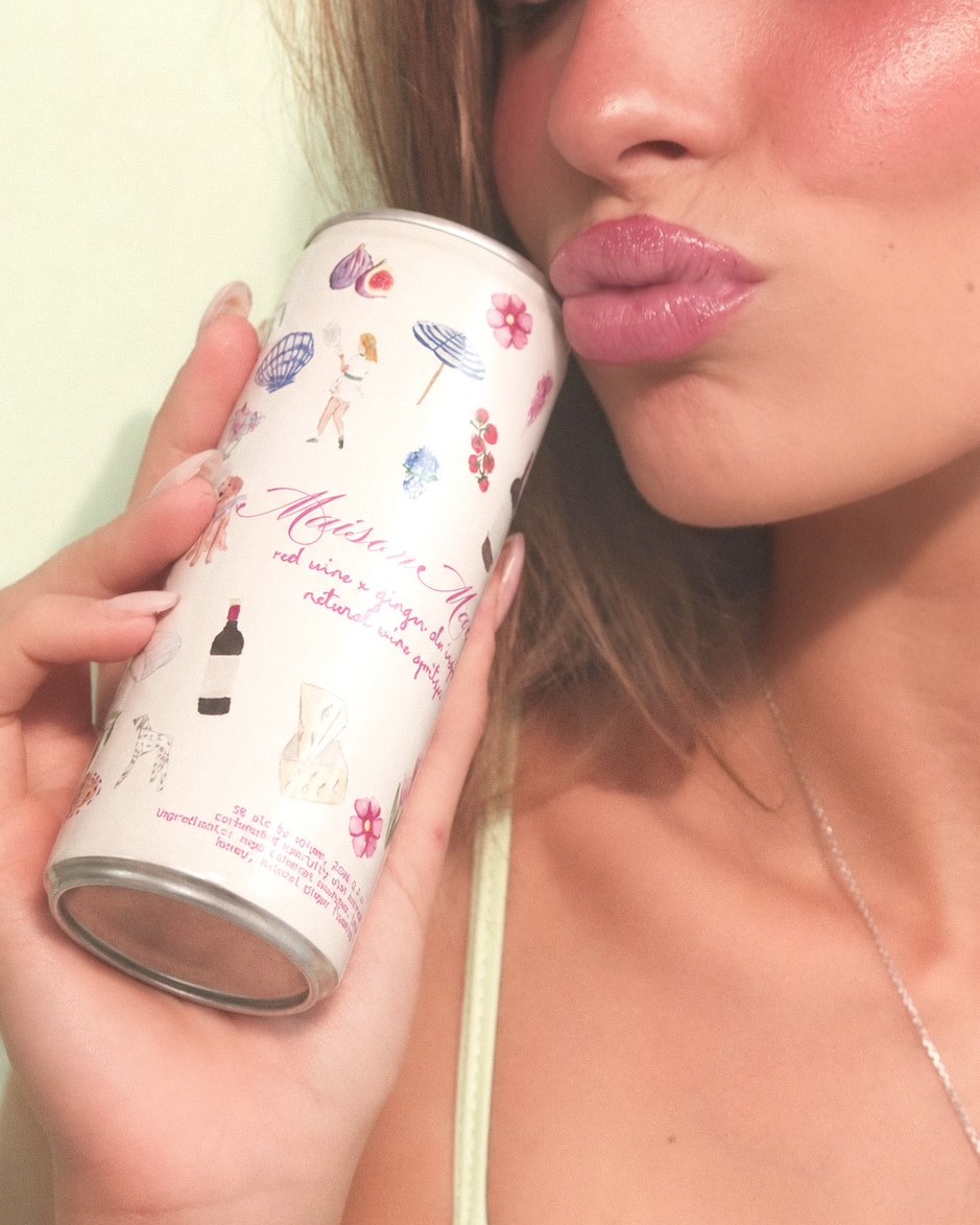 a maison maxine red wine spritzer can held up to a kiss